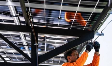 Technician installing solar panels on a mounting structure